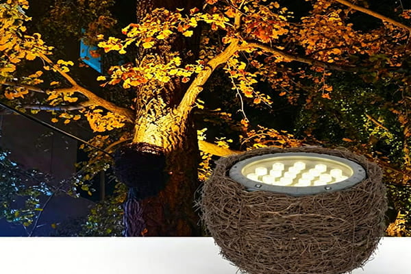 Floodlight hidden in a decorative bird's nest on a tree branch